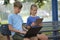 Two children teenager boy with laptop computer and young girl with digital tablet looking at screens outdoors sitting on