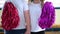 Two children with white T-shirts are standing and waving pompoms. Support group during the competition in kindergarten