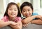 Two Chinese Children Relaxing On Sofa At Home