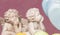 Two chipped cherub statues with chins on hands surrounded by pastel hearts isolated on pink background for Valentine`s Day