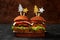 Two Christmas burgers with tomatoes, olives, cream cheese, onions, cutlets on a festive dark table, New Year\\\'s food concept.