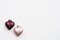 Two Christmas decorations in the form of a pink and plum-colored heart with copy space on a white background