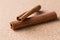 Two cinnamon sticks on corkwood background.