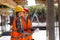 Two civil engineers dressed in orange work vests and helmets discuss the construction process on the building site near