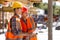 Two civil engineers dressed in orange work vests and helmets discuss the construction process on the building site near