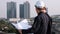 Two civil engineers wear helmet to inspect project and blueprints of building in construction site.