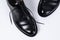 Two classical black leather shoes on white background.