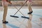 Two cleaners with mop cleaning marble floor outdoors. Cleaning service