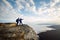 Two climbers standing on top of summit above clouds in the mountains. Hiker man pointing with his hand discussing route