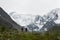 Two climbers walk along the crest of the mountain against the background of the snow-capped peaks of ` Belukha`