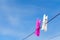 Two clothespin pink and white on a clothesline  on a blue sky