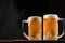 Two cold mugs with beer, with overflowing foam, on wooden table and dark background, space for writing