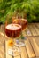 Two cold rose wine glasses served on outdoor terrace in garden with flowers in sunny day