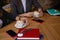 Two colleagues having business lunch, cofee break. Hands holding cappuccino cups. Notebooks, smartphones, pens and glasses on