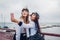 Two college women students of Marine academy taking selfie by sea wearing uniform. Happy friends having fun