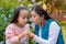 Two Colombian Latin American girls blow a dandelion in the garden of the house