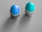 Two colored boiled eggs in ceramic cup or holder on grey background