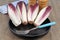 Two-colored endives in a black plate with a fork close-up