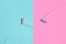 Two colored wooden pegs and small rope lie on texture background of fashion pastel blue and pink colors paper in minimal concept