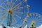 Two colorful Ferris wheels silhouetted against a bright blue sky