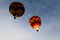 Two colorful hot air balloons float away into the blue sky
