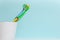 Two colorful kids toothbrushes in white cup on cyan  color background. Space for text.  Dental care concept