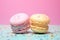 two colorful macaroons separated by space on pastel backdrop