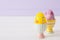 Two colorful painted Easter eggs in vibrant modern egg stands on pastel lilac background