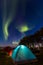 Two colorful sleeping tents under a night sky with green northern lights