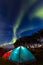 Two colorful sleeping tents under a night sky with green northern lights