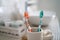 Two colorful toothbrushes stand in a ceramic glass against the background of the washbasin and other accessories in the