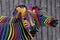 Two colorful zebras painted in the colors of the rainbow cuddle on the background of a wooden fence