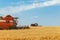 Two combines harvests ripe wheat in the grain field