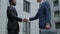 Two company workers in formal suits shaking hands, colleagues greeting, merger