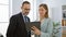 Two confident business workers standing together, enjoying their work at the office, using touchpad device amid a professional