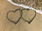 Two connected Hearts drawn on the beach sand with sea waves