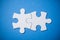 Two connected jigsaw puzzle pieces on blue background. The concept of finding the right solutions in teamwork