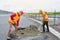 Two construction workers shovel concrete while building a road