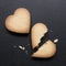 Two cookies in the shape of heart, one of them is broken on black background. Cracked heart shaped cookie as concept of breakup