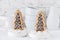 Two cookies shaped as christmas trees with chocolate and sugar glaze in bowls with coarse sugar on white background
