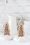 Two cookies shaped as christmas trees with chocolate and sugar glaze in bowls with coarse sugar on white background