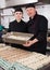 Two cooks holding baking tray with cannelloni