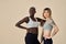 Two cool diverse fit girls wearing sportswear standing on background. Copy space