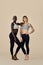 Two cool diverse fit girls wearing sportswear standing on background, vertical.