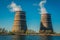 Two cooling towers of a nuclear power plant near a lake against a blue sky. Ecological energy production.