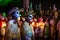 Two costumed cowboys with skull make-up in front of a line of costumed people with candles and graveyard at the event for dias de