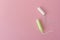 Two cotton tampons with light green applicator and without applicator on a pink background. Hygienic types of tampons.