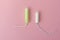 Two cotton tampons with light green applicator and without applicator on a pink background. Hygienic types of tampons.