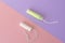 Two cotton tampons with light green applicator and without applicator on a pink and violet background. Hygienic types of tampons.