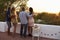 Two couples admire view from rooftop at sunset, full length